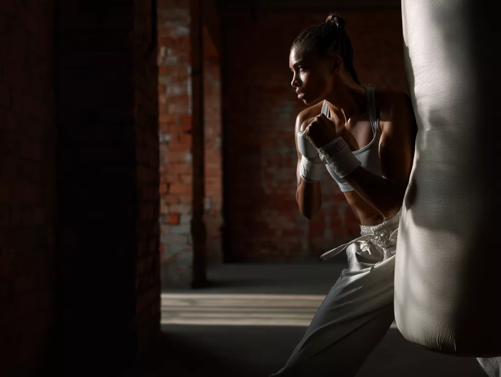 Coach de boxe Paris avec une femme à l'entraînement de boxe anglaise au sac de frappe