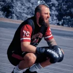 Boxeur accroupi récupérant et écoutant les conseils de John Mbumba lors du cours de boxe à Paris 13.